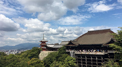 Tempel med terrass och turister som beundrar utsikten över Kyoto.